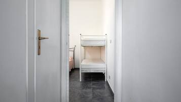 Un couloir étroit avec un lit superposé et une porte dotée d’une poignée.