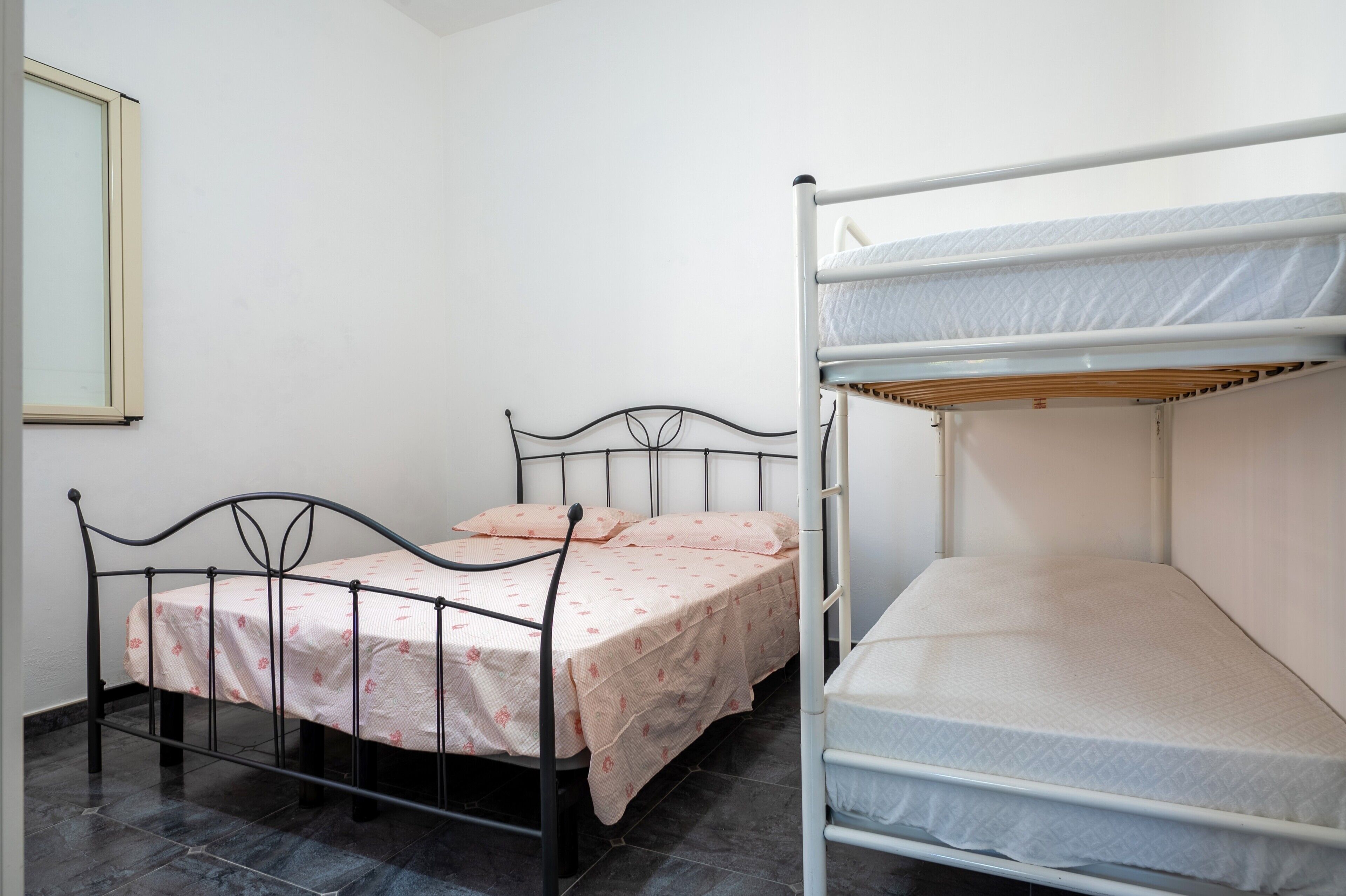 Une chambre avec un lit simple, un lit superposé et une fenêtre.