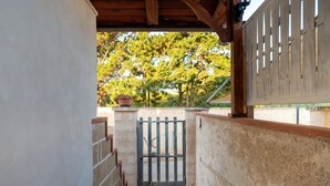 Un espace extérieur abrité, doté d’une entrée fermée par un portail, d’une clôture en bois et offrant une vue sur les arbres.