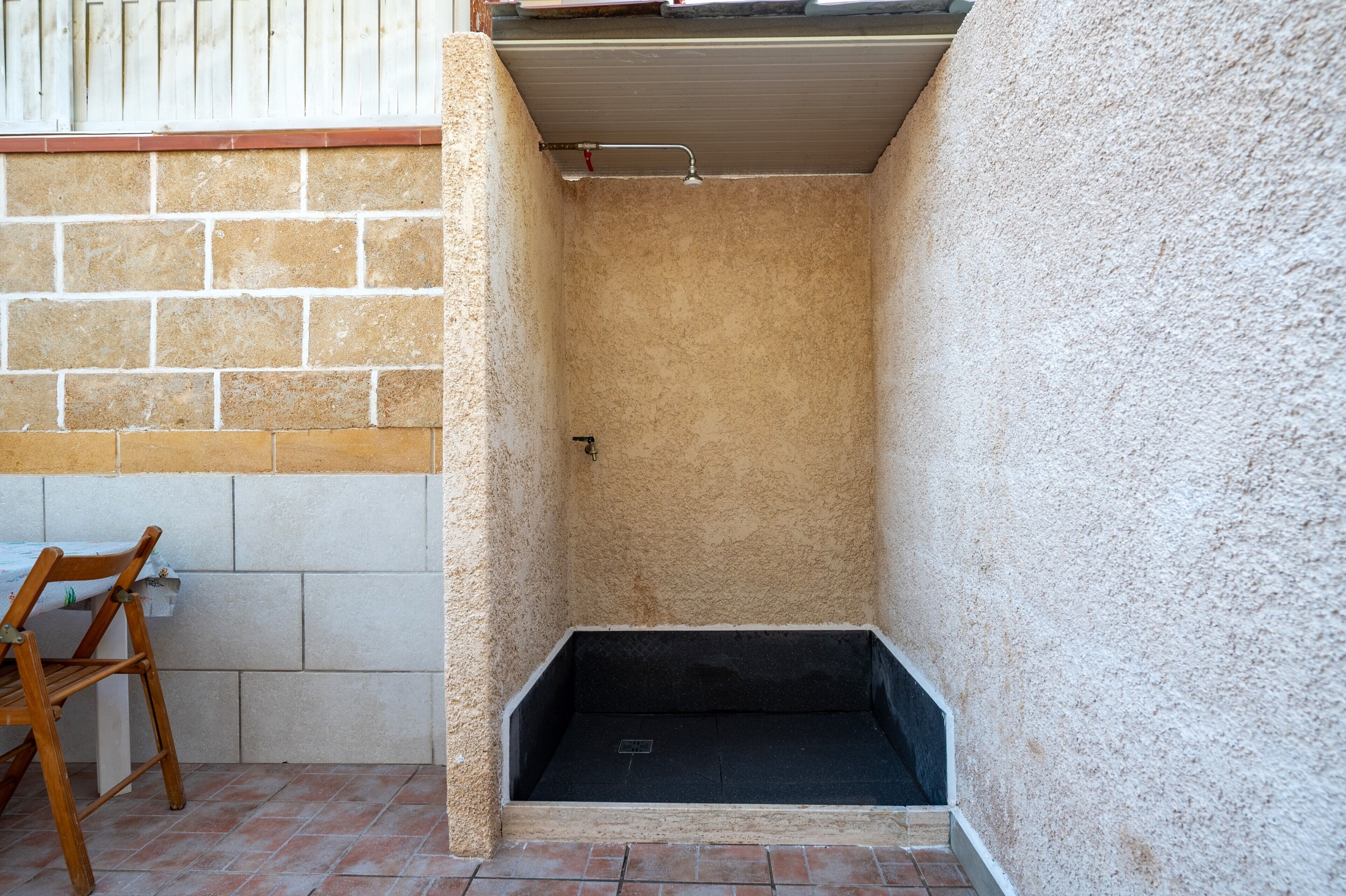 Un petit espace clos comprenant une douche, une chaise et une table.