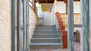 Un escalier menant à une pièce dotée d’une fenêtre, d’une porte et d’une chaise.