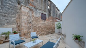 An outdoor seating area with stone walls, a metal table, and chairs.