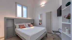 Ein modernes Schlafzimmer mit Bett, Einbauschränken, Heizkörper und einem an der Wand befestigten Fernseher.