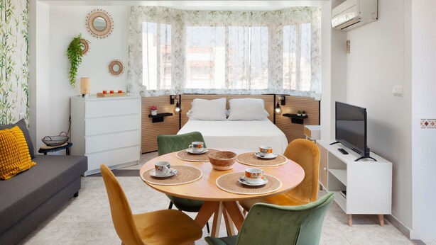Une chambre d’hôtel moderne équipée d’un lit, d’une télévision, d’un bureau et d’un coin repas avec des chaises et une table.