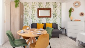 Un coin repas comprenant une table ronde, des chaises et un canapé avec des coussins.