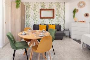A dining area with a round table, chairs, and a sofa with cushions.