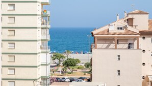 Un bâtiment situé sur la côte, doté de balcons donnant sur la mer, d’un espace de stationnement et d’une plage en arrière-plan.