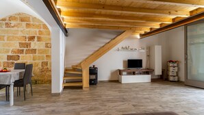 A modern interior with a dining area, a staircase, a TV, and storage units. - Apartment 'Casa Incanto' with Private Garden and Air Conditioning (Presicce-Acquarica)