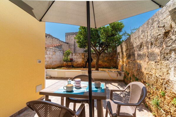 Une terrasse avec une table, des chaises et un parasol.