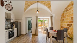 A modern kitchen with a stone archway leading to a dining area with a table and chairs. - Apartment 'Casa Incanto' with Private Garden and Air Conditioning (Presicce-Acquarica)