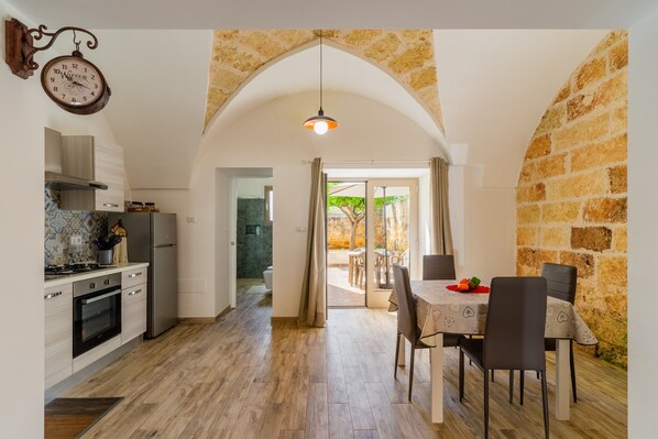 A modern kitchen with a stone archway leading to a dining area with a table and chairs.