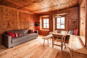 Un interior de madera con sofá, banco, mesa y ventana.