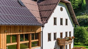 A two-story building with a sloped roof, large windows, and wooden balconies with flower boxes. - Apartment 'Josephus - Domicilium I' with Mountain View, Shared Terrace and Wi-Fi (Madonna di Senales)
