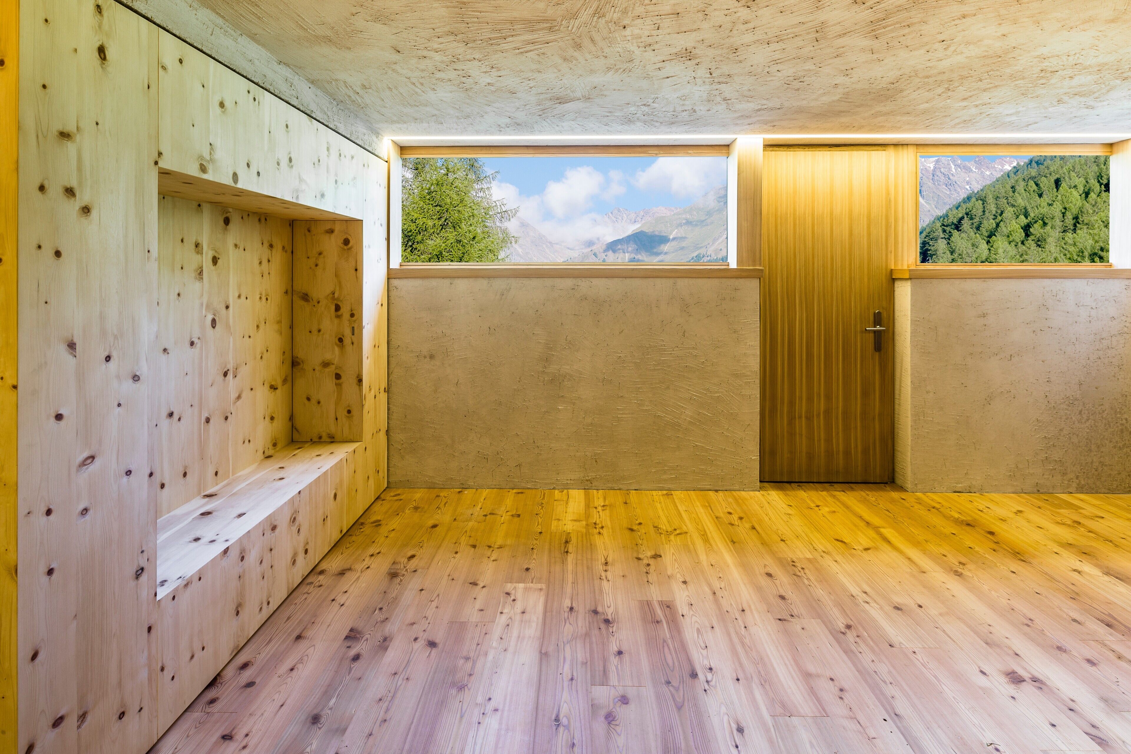 Ein Zimmer mit Holzwänden, einer Holztür und einem Fenster mit Bergblick.
