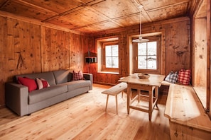 A wooden interior with a sofa, bench, table, and window.