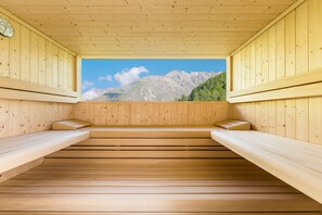 Uma sauna de madeira com bancos e vista para montanhas.