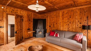 A wooden interior with a sofa, a fireplace, and a wooden bowl on the floor. - Apartment 'Josephus - Domicilium I' with Mountain View, Shared Terrace and Wi-Fi (Madonna di Senales)