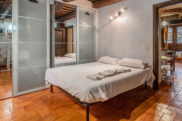A bedroom with a bed, a sliding glass door, and a wooden floor.