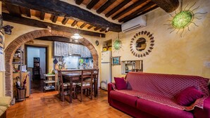 Una sala de estar acogedora con un sofá rojo, un comedor con muebles de madera y una cocina visible a través de un arco.