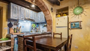 Una cocina con armarios de madera, un arco de ladrillo, una mesa de comedor con sillas y un adorno en la pared.