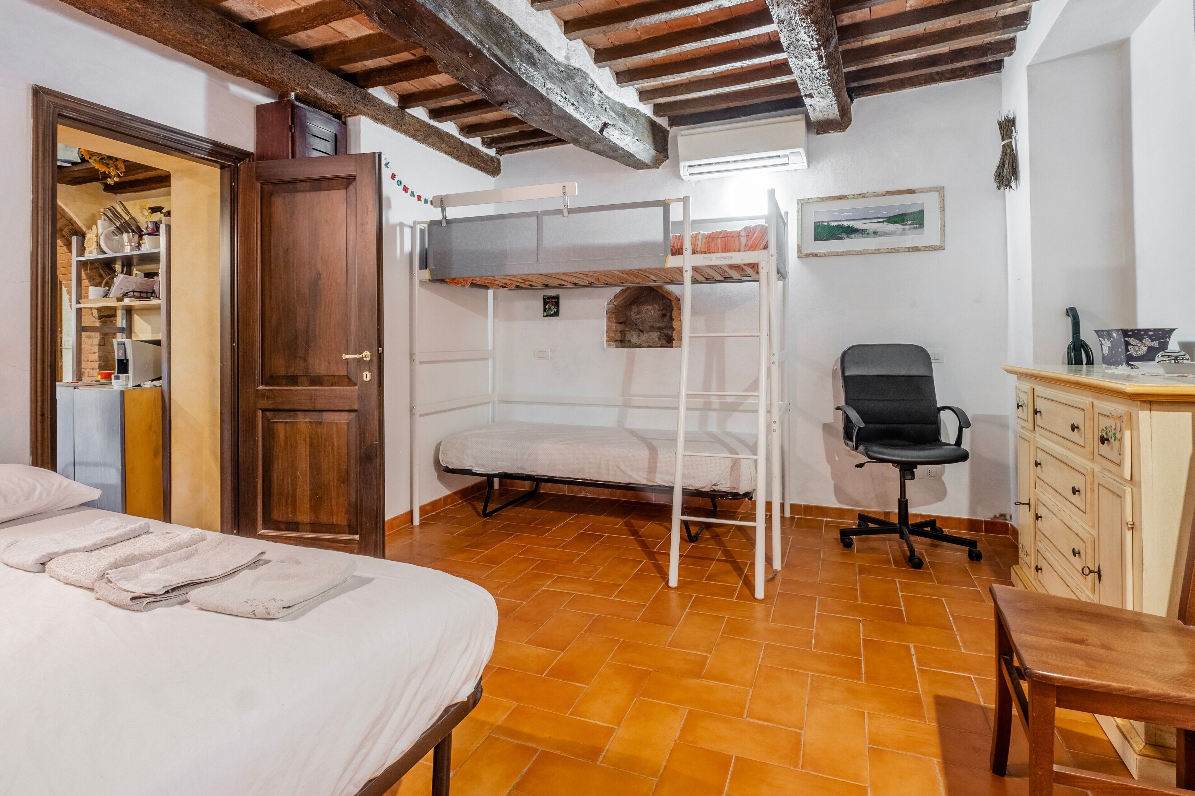 Een slaapkamer met een stapelbed, een bureau, een stoel en een kledingkast.