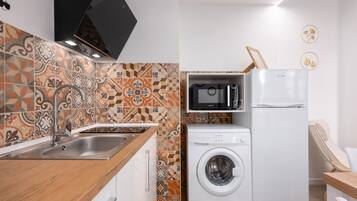 Una cocina compacta con lavadora, microondas y pileta.