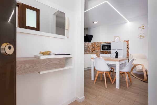 Une cuisine moderne avec des meubles blancs, un four à micro-ondes et un réfrigérateur.
