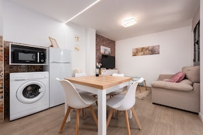 Un espace de vie compact comprenant un lave-linge, un four à micro-ondes, un réfrigérateur, une table à manger et un canapé.