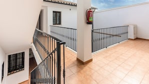 A multi-level building with a tiled floor, black railings, and a fire extinguisher.