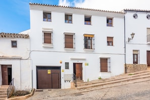 Un bâtiment blanc avec de nombreuses fenêtres, une porte marron et un escalier menant à l’entrée.