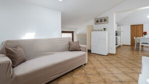 A modern living room with a sofa, a dining area, and a kitchen in the background. - 5 minutes from Lake Garda, Dimora "Charme of Butterfly (Cavaion Veronese)