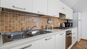 A modern kitchen with white cabinets, a stainless steel sink, a gas stove, and a microwave. - 5 minutes from Lake Garda, Dimora "Charme of Butterfly (Cavaion Veronese)
