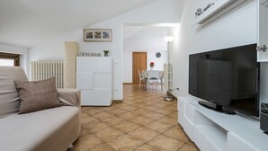 A modern living room with a sofa, a flat-screen TV, a radiator, and a dining area with a table and chairs. - 5 minutes from Lake Garda, Dimora "Charme of Butterfly (Cavaion Veronese)
