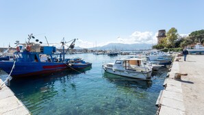 A marina with boats docked, clear water, and a stone pier.