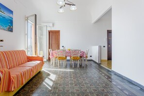 Una habitación con sofá, mesa de comedor, sillas y suelo con baldosas estampadas.