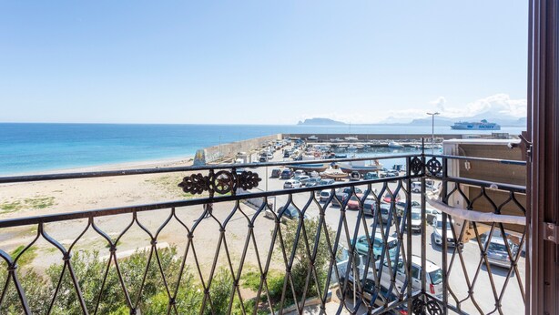 A balcony with a view of a beach and parking area.