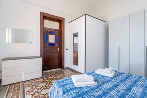 Un dormitorio con cama, cómoda, armario y puerta con espejo.