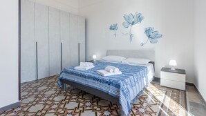 A bedroom with a bed, nightstands, a wardrobe, and a patterned floor.