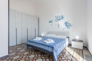 Un dormitorio con cama, mesitas de noche, armario y suelo estampado.