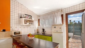 A kitchen with a central island, bar stools, a microwave, a coffee maker, and a refrigerator. - Vacation Home 'Haus Brigitte' with Shared Pool, Wi-Fi and Air Conditioning (Playa del Inglés)