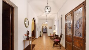 A hallway with a wooden door, a mirror, a small table with decorative items, a chair, and a lamp. - Chalet "Casa Barreto" with Sea View, 3 Private Terraces & Wi-Fi (Puerto de la Cruz)