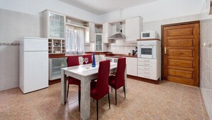 A compact kitchen with white cabinets, a built-in microwave, and a dining area with a table and chairs. - Chalet "Casa Barreto" with Sea View, 3 Private Terraces & Wi-Fi (Puerto de la Cruz)