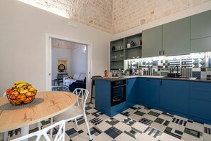 Une cuisine compacte avec des meubles bleus, un îlot central et un coin repas comprenant une table ronde et des chaises.