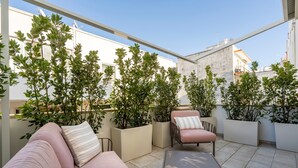 A rooftop patio with a sofa, armchair, and table, surrounded by potted plants. - Holiday Apartment "Civico40 Suite" with 2 Private Terraces, Balcony & Wi-Fi (Locorotondo)