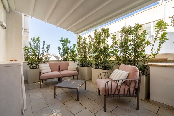 An outdoor patio area with two sofas, a coffee table, and potted plants.