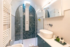 A modern bathroom with a glass-enclosed shower, a white sink, and a mirror above the vanity.
