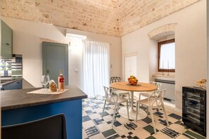 A modern kitchen with a built-in island, a dining area with a round table and chairs, and a patterned floor.