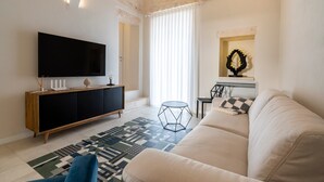 A modern living room with a flat-screen TV, a wooden cabinet, a patterned rug, a round side table, and a sofa. - Holiday Apartment "Civico40 Suite" with 2 Private Terraces, Balcony & Wi-Fi (Locorotondo)