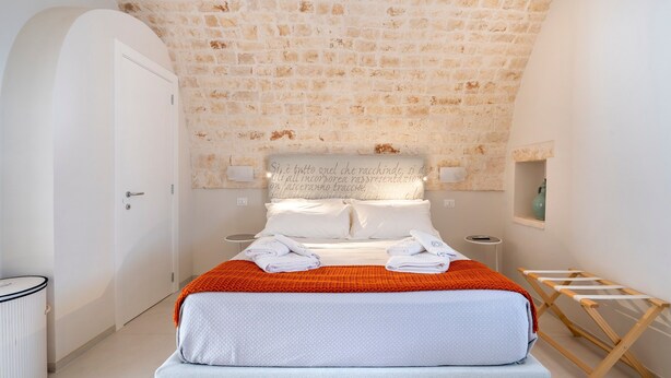 A bedroom with a stone ceiling, a bed with white linens, a wooden side table, and a small shelf with a vase. - Holiday Apartment "Civico40 Suite" with 2 Private Terraces, Balcony & Wi-Fi (Locorotondo)