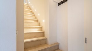 A staircase with a handrail, a light switch, and a door at the bottom. - Holiday Apartment "Civico40 Suite" with 2 Private Terraces, Balcony & Wi-Fi (Locorotondo)